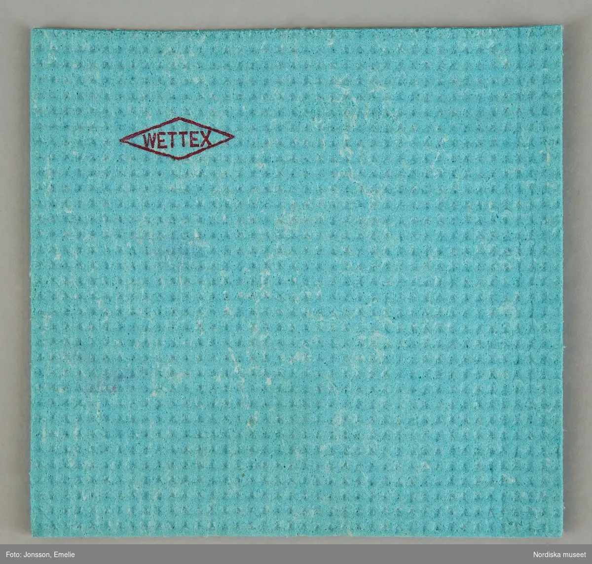 Huvudliggaren:
"Hushållsartiklar:
a) diskborste, skaft av blå nylon, borst vit nylon, märkt 'Gloria Husqvarna', skaft L 21 cm.
b) torkduk, 'Wettex', cellulosa, blågrön, mått 20 x 20 cm.
c) tvättmedelsförpackning i blå-röd-vit kartong 'JÖR'. H 20,3 cm Br. 13,5 cm.
d) Toalettpappersrulle, vit, märkt i blått 'Edet kräpp, H 11 cm
Prov på hushållsartiklar i ett Stockholmshushåll 1964."