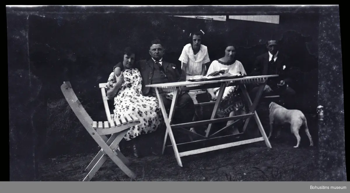 Fem personer sittandes i en trädgårdsgrupp tillsammans med en hud.