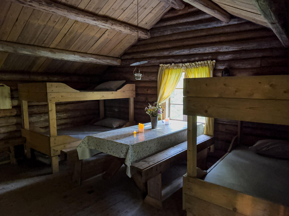 Interiør i skogskoia Bangdalsbruket. Det står 2 køyesenger og et bord i rommet.
