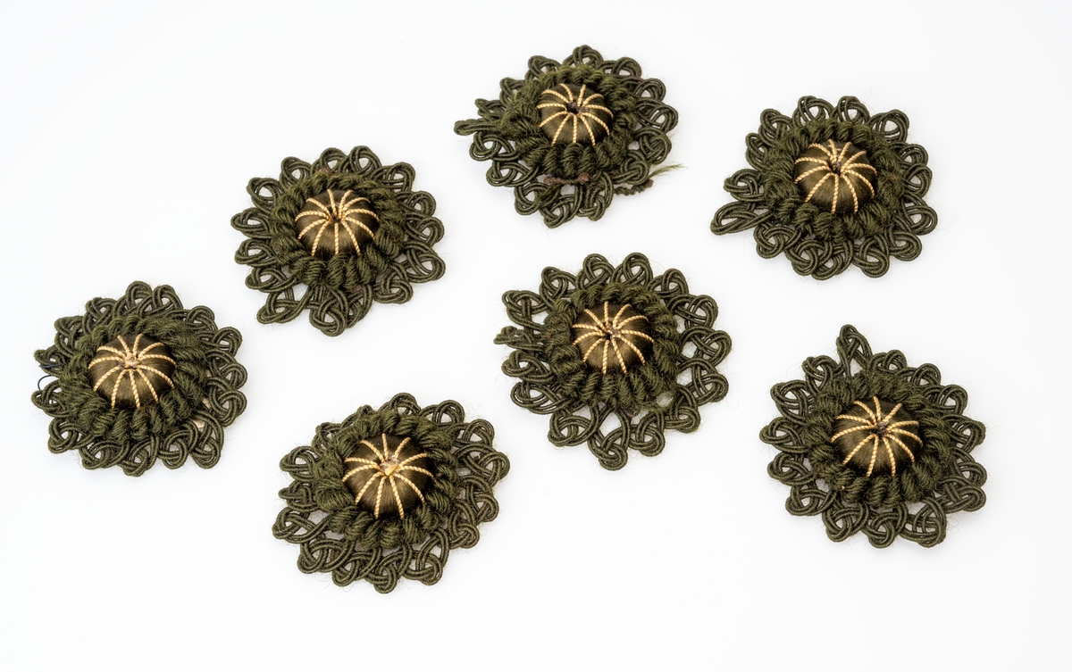 7 identiske rosetter brukt til møbler (møbelpossement). I midten er det en possementform av tre trukket med grønn silketråd og dekorert med tynn gulgrønn silkesnor. Rosettene er laget av grønn ulltråd og grønn silketråd.