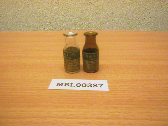 To sylindriske, små medisinflasker fra Moss Glasværk - en i brunt og en i klart glass.