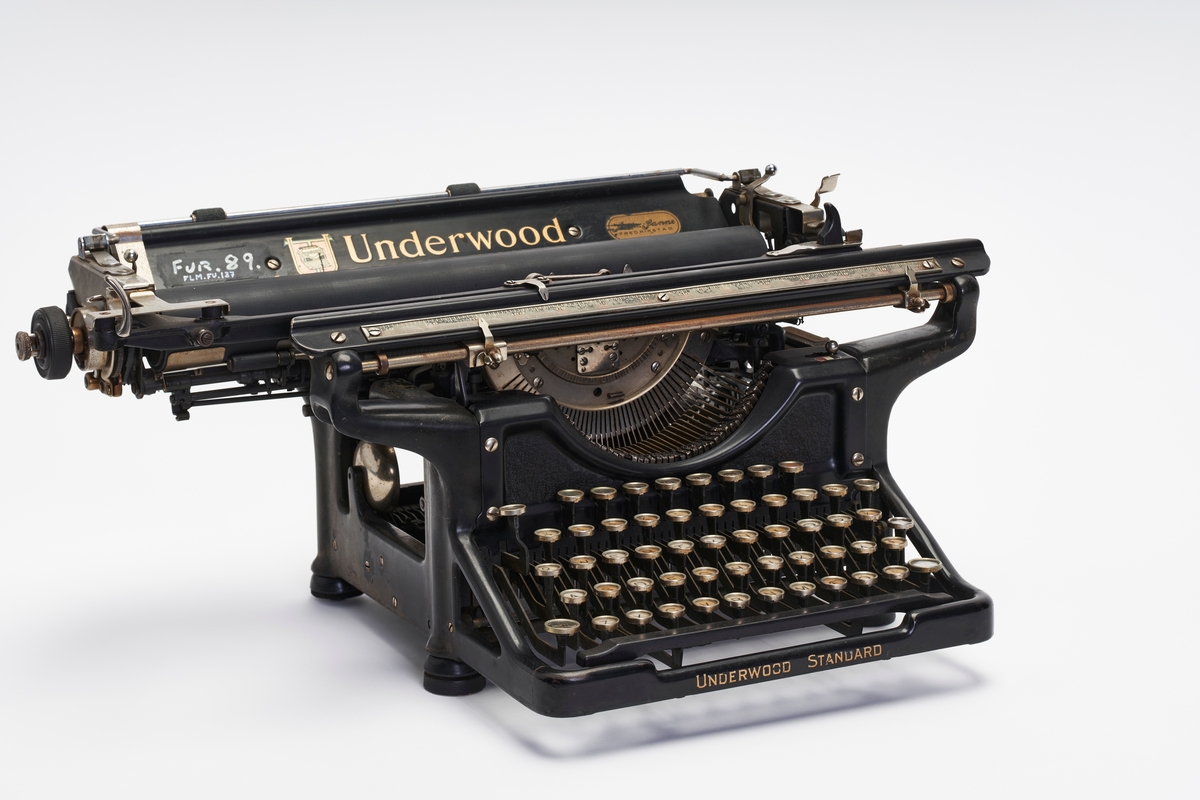 Manuell skrivemaskin med bred valse. Fargebånd med rød og sort farge sitter i.