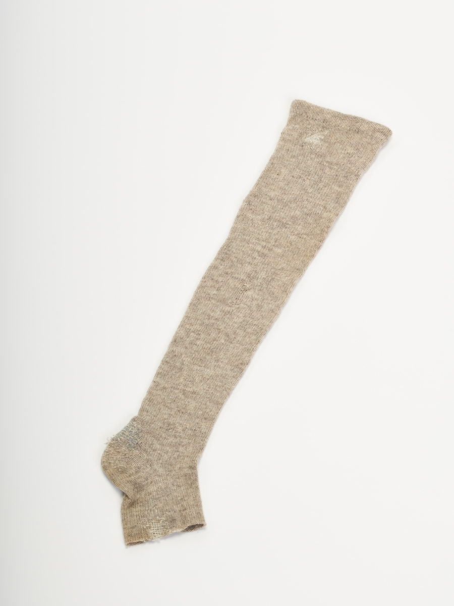 Vanlig strømpefasong med brettet kant øverst. Meget mye slitasjer, rift i hæl, tupp av sokk og under brettekant.