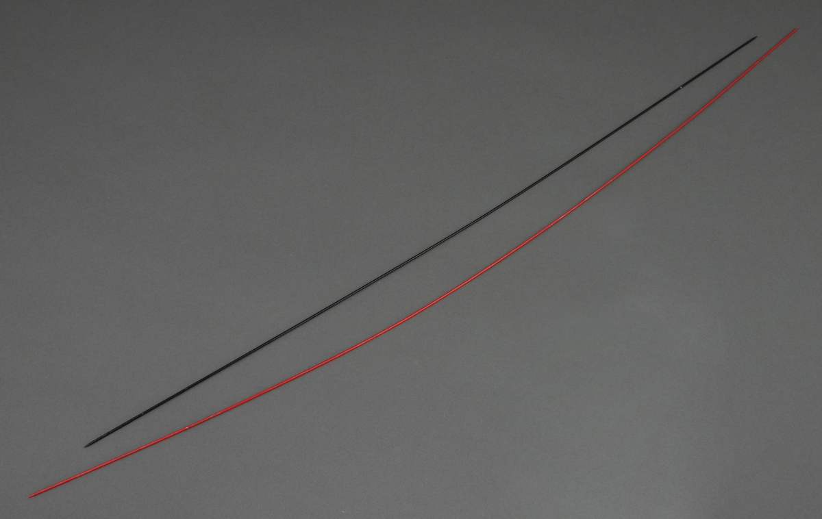 To stålpinner, lakkert i henholdsvis rødt og svart. Pinnene har en spiss avslutning i begge ender.