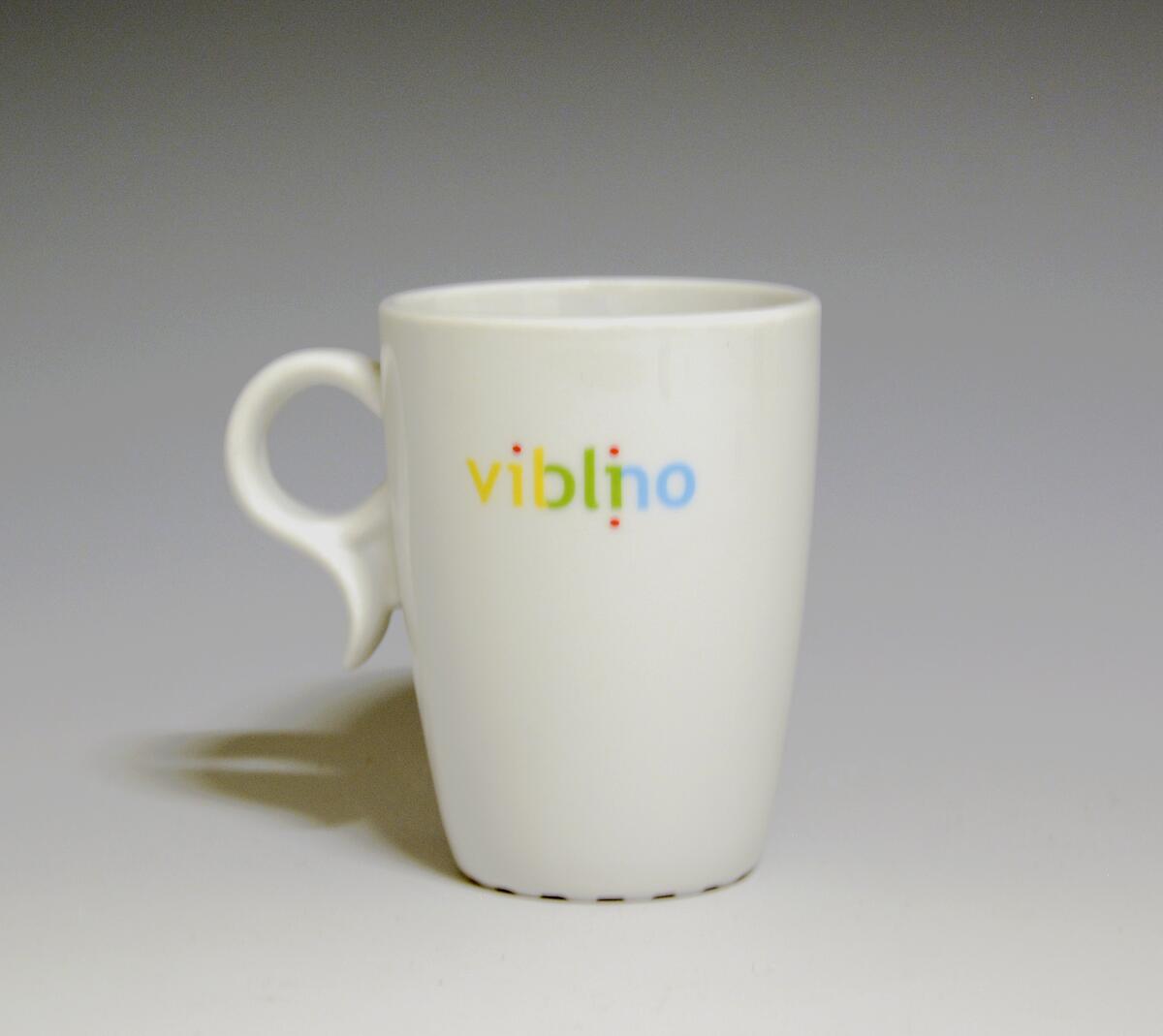 Krus av porselen med  hvit glasur. Trykkdekor med påskriften: "Vigo" i gult og sort på den ene siden, og "Viblino" i gult, rødt, grønt og blått på den andre siden.
Modell: 2731, Victor