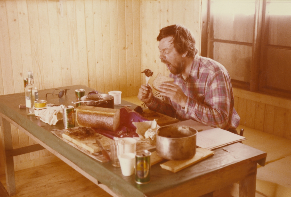 Fra Skansbukta. A. Ernstsen skrev under bildet:  Olav spiser selkjøt, reinkjøt og drikker sermek. Originalen returnert til giveren.