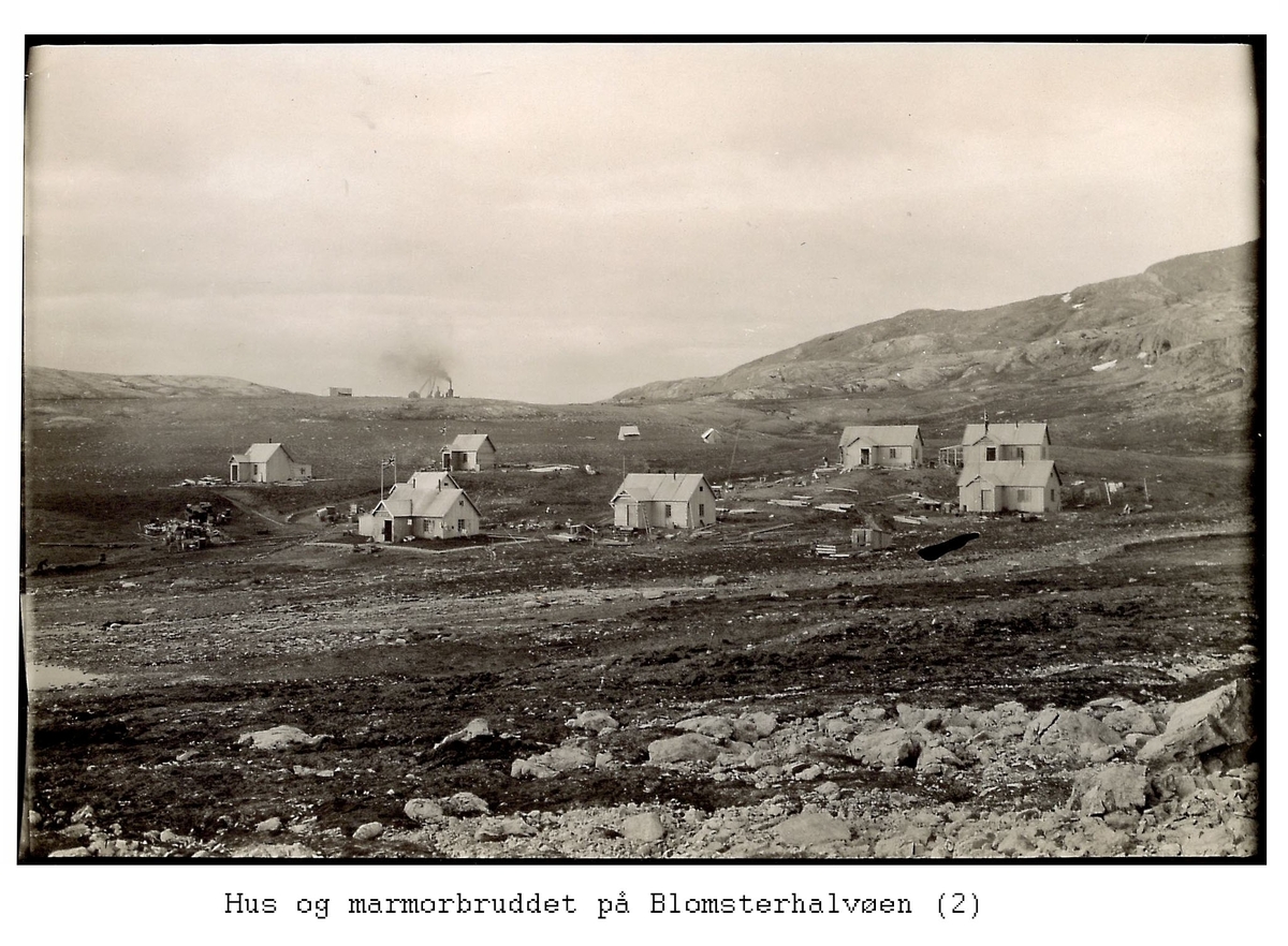 Alf Frantzens fotosamling: Åtte hus og to telt i Northern Exploration Company’s marmorbrudd i London på Blomstrandhalvøya. Marmorbruddet bakerst mot himmelen. 1912.   (De to hus bakerst til venstre står ennå, de fire til høyre ble flyttet til Ny-Ålesund tidlig på 1950-tallet).