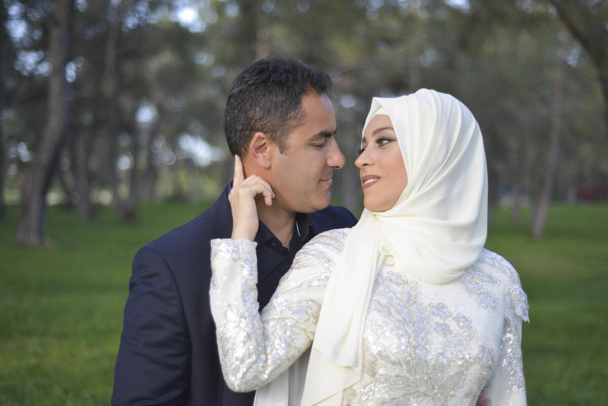 Bryllupsfotografi av et muslimsk ektepar, tatt ute i en park.