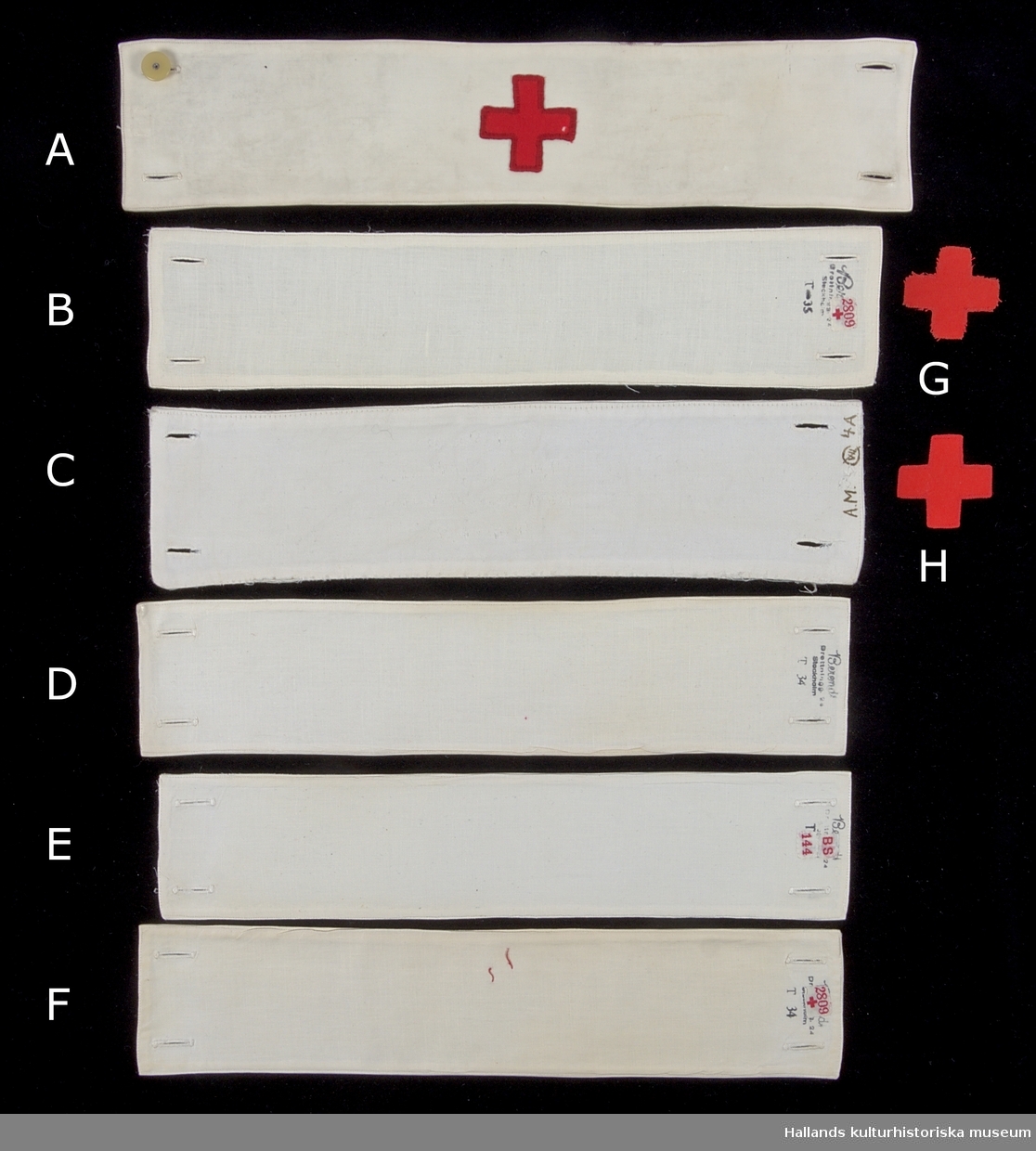 Samling av armbindlar tillhörande sjuksköterska.

A: Armbindel av fodrad vit bomullsväv. Manglad och stärkt. Armbindeln bär Röda Korsets symbol i rött bomullstyg. Hålls ihop med två manschettknappar, varav den ena saknas. På avigsidan finns en etikett med röd text: "2809" åtföljt av ett rött kors. Bredvid etiketten en tillverkarstämpel i svart bläck (se foto)
Längd: 375 mm. Höjd: 77 mm.

B: Armbindel av fodrad vit bomullsväv. Manglad och stärkt. Två förstärkta hål på vardera kortsida för manschettknappar. På avigsidan finns en etikett med röd text: "2809" åtföljt av ett rött kors. Bredvid etiketten en tillverkarstämpel i svart bläck (se foto), samt "T-35".
Längd: 350 mm. Höjd: 74 mm.

C: Armbindel av fodrad vit bomullsväv. Manglad och stärkt. Två knapphål på vardera kortsida.. Märkt med bläck längs ena kortsidan: "A.M. 4.A" samt en figur som består av tecknen "VII" omgärdat av en överstruken ring. 
Längd: 345 mm. Höjd: 85 mm.

D: Armbindel av fodrad vit bomullsväv. Manglad och stärkt. Två knapphål på vardera kortsida. Längs en av kortsidorna finns en tillverkarstämpel samt texten: "T 34". 
Längd: 345 mm. Höjd 77 mm.

E: Armbindel av fodrad vit bomullsväv. Manglad och stärkt. Två knapphål på vardera kortsida. På en av kortsidorna en svårtydd tillverkarstämpel med svart bläck; ovanför stämpel sitter en etikett med röd text: "BS 144". 
Längd: 340 mm. Höjd: 73 mm.

F: Armbindel av fodrad vit bomullsväv. Manglad och stärkt. Två knapphål på vardera kortsida. I mitten av armbandet finns rester av röd tråd vilket troligtvis är ett spår efter ett tygmärke. På en av avigsidorna en etikett med röd text: "2809" åtföljt av ett rött kors. Under etiketten en tillverkarstämpel i svart bläck (se foto), samt "T 34". 
Längd: 345. Höjd: 72 mm.

G: Tygmärke av röd bomullsväv föreställande röda korsets symbol. Tygmärket saknar sömmar längs kanterna och är därmed fransigt - ofärdigställt. Tygmärket skall fästas i armbindel.
Längd: 45 mm. Höjd 45 mm.

H: Tygmärke av röd bomullsväv föreställande röda korsets symbol. Sömmar längs kanterna. Tygmärket skall fästas i armbindel.
Längd: 45 mm. Höjd 45 mm.