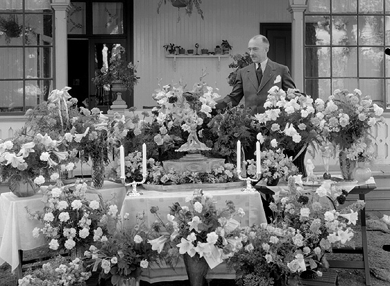 Man omgiven av blomsterarrangemang.
Fotografens ant: Maskininspektör Olsson 18/7 1936.
