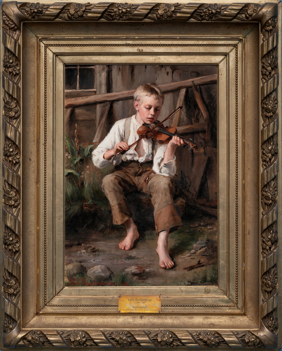 Liten barbent gutt med åpen skjorte sittende med en violin under haken foran en uthusvegg.