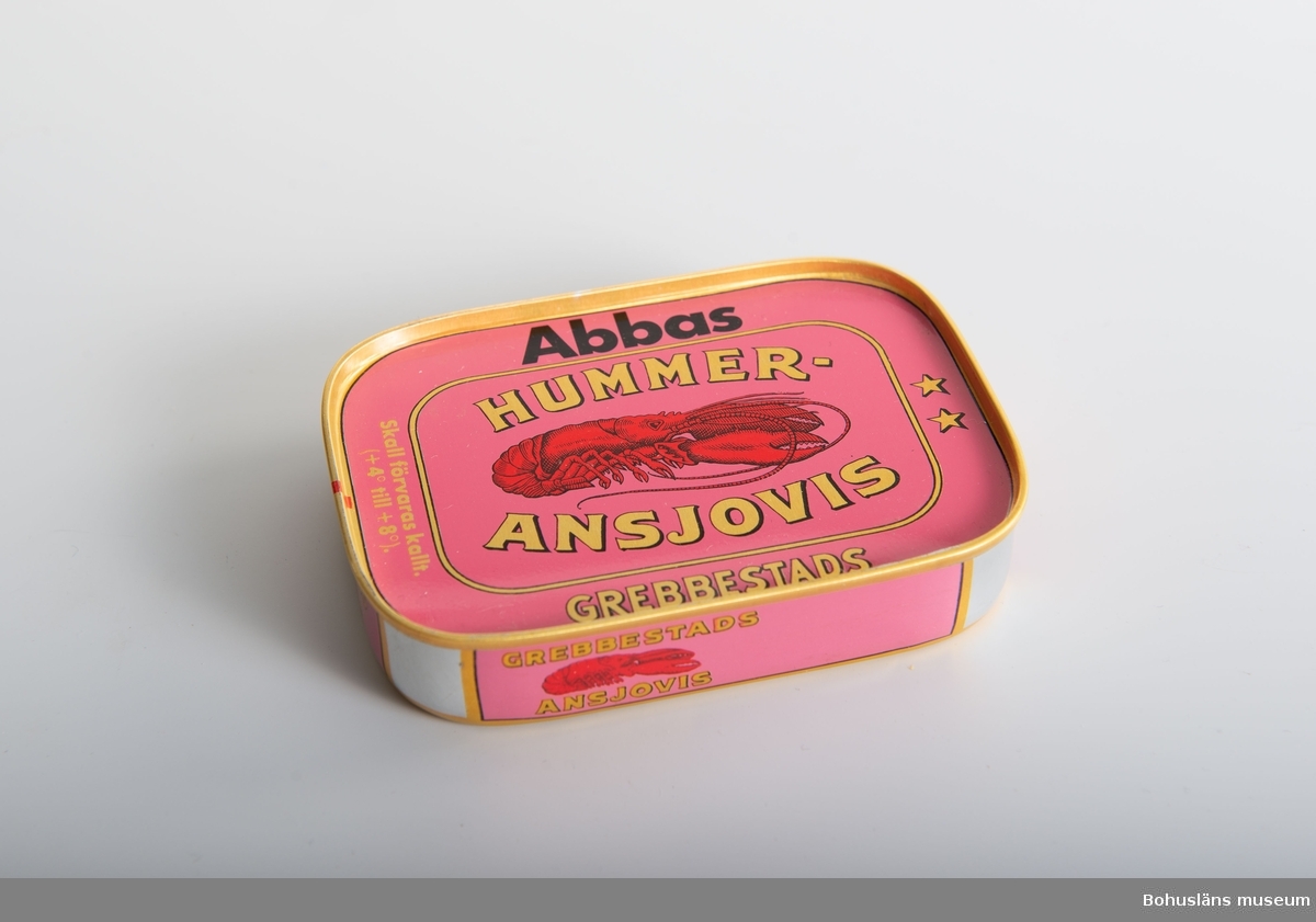 Rektangulär burk med tryck direkt på plåten i rosa, rött, svart och guldfärg, bild av hummer och text: "Abbas hummeransjovis Grebbestads".
På baksidan innehållsdeklaration och prismärkningskod.

Om givaren se UM026667

På 1990-talet bytte produkten namn och utseende. Förr hette det hummeransjovis vilket EU förbjöd pga att det inte fanns någon hummer i produkten. Eftersom den rosaröda burken var så välkänd och inarbetad så ledde inte förändringen till något ytterligare problem.