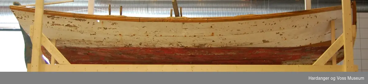 Lettbåt fra selfanger med to tofter i baugen med en lav vegg imellom, to par tollepinner på styrbord side, bredt sete i akter, samt ror med rorkult og en åragaffel festet til akterspeilet. Båten er hovedsakelig hvitmalt med okergule kanter og seter, blått ror, og den er rødmalt under bunnen. Båten er klinkbygget.
