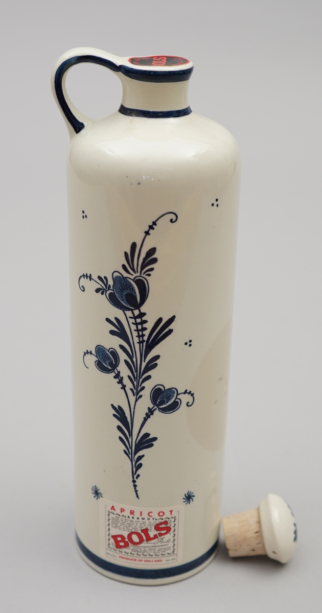 Kvit flaske med nederlandsk blå dekormåling. Pappkartong med nederlkandske folkelege motiv.
