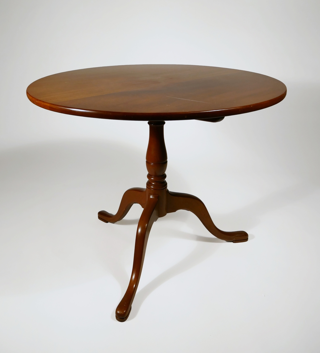 Fällbord av mahogny. Rund skiva med svarvat ben och tre fötter. Under bordsskivan är möbeln märkt J.G.A. = J.G. Axelssons snickeriverkstad.