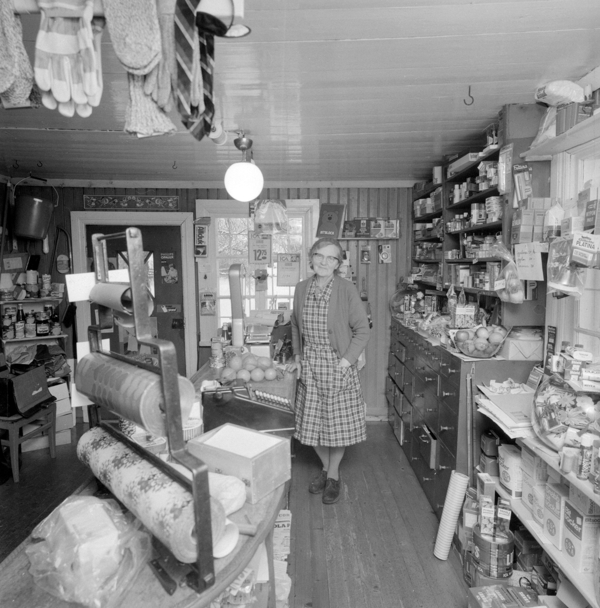 Eva Nilsson i Kävarp visar sin lilla ICA-affär i Ulrika, vid tiden sannolikt Sveriges minsta. I det lite avsides Kävarp hade hennes farbror öppnat handelsrörelsen redan år 1888. Efterhand hade hennes far tagit över butiken och efter honom följde Eva och hennes bror Arvid. Här ett reportage från dagarna efter nyåret 1975.
