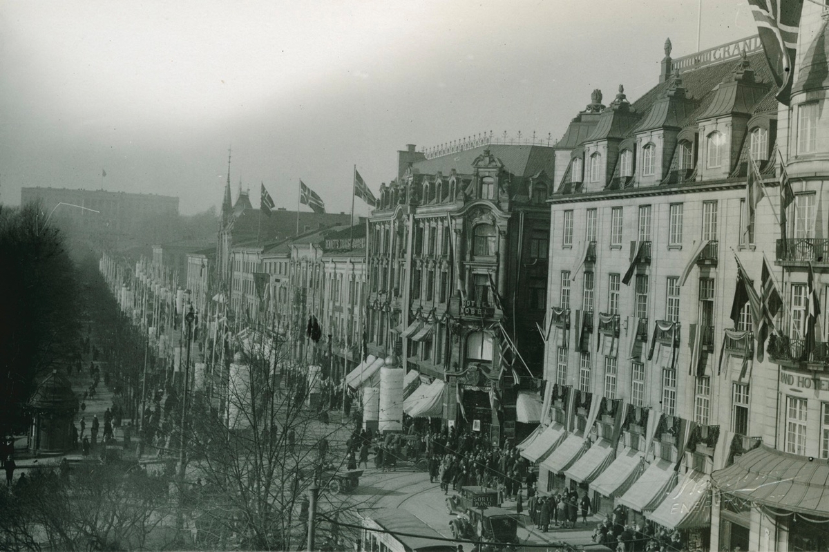 Karl Johans gate med Grand Hotel, pyntet med flagg. Slottet i bakgrunnen.