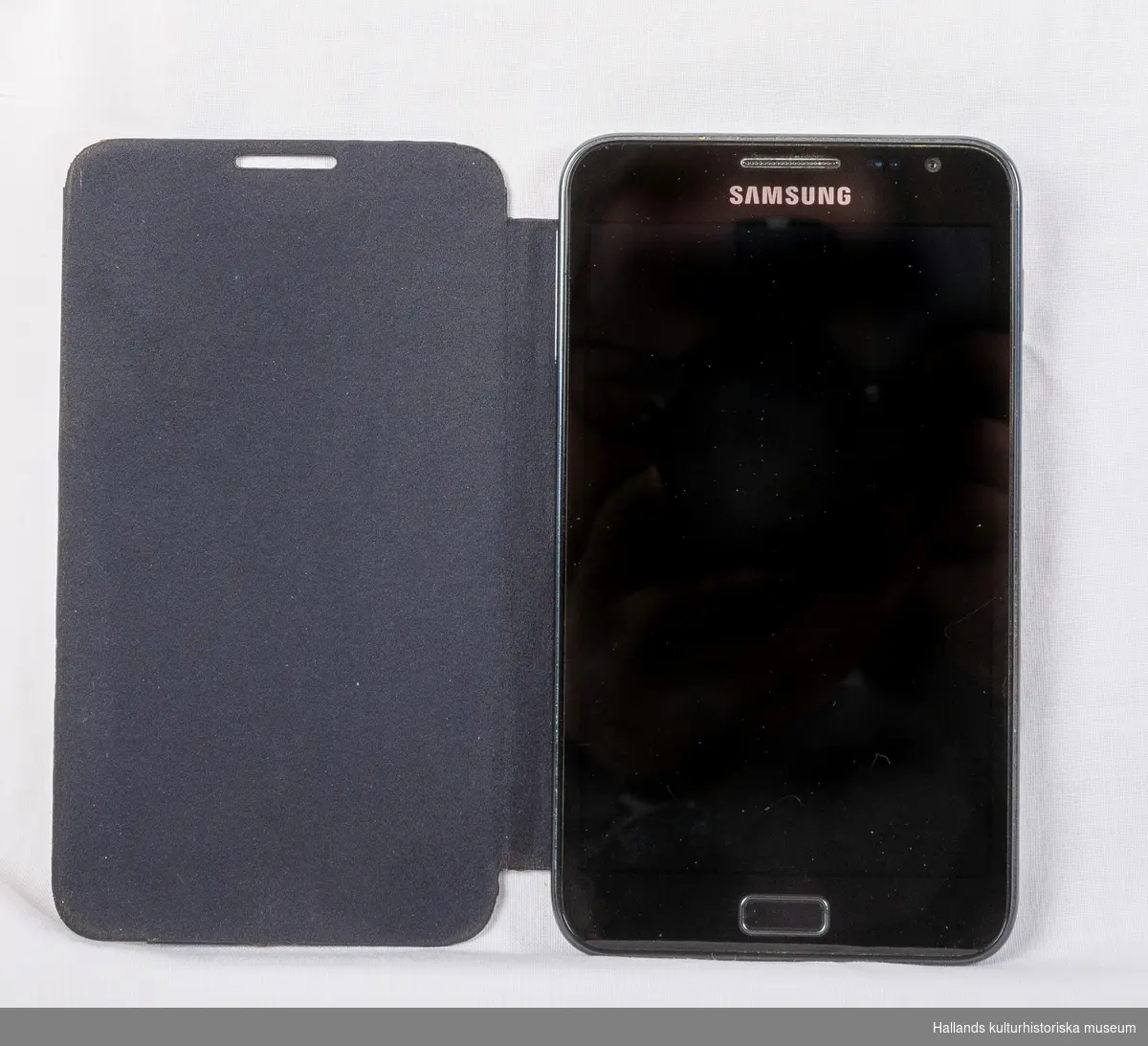 Samsung Galaxy Note (Tillverkare: Samsung, modell: Galaxy Note) med yttre skal av svart hårdplast och metall. Telefonen har ett vikbart fodral av svart konstläder.

På telefonens framsida en digital skärm med sensor för tryck, en tryckknapp, högtalare, kameraoptik, samt en märkning: Samsung. På telefonens baksida kameraoptik, en lysdiod för blixtljus, samt en märkning: Samsung. Baksidan går att knäppa loss för åtkomst av batteri och telefonkort (sim). I telefonen sitter ett simkort från teleoperatören Telia.