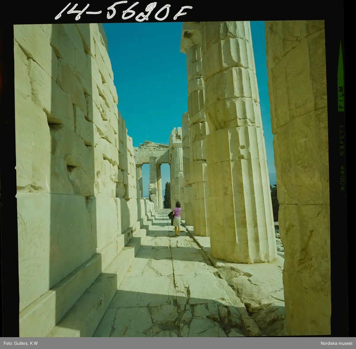 2795 Grekland Akropolis med runierna av bl.a. templen Parthenon och Erechtheion. En kvinna mellan rader av kolonner.