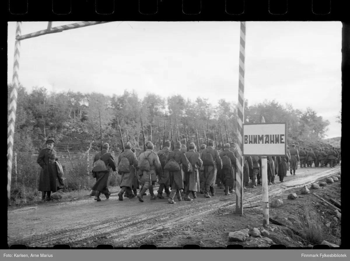 Russiske soldater på grensa i Sør-Varanger ved grensebom i Storskog. Soldatene bærer på våpen. I følge notat tilhørende bildene var bildene tatt av en russisk fotograf 

I foto kan man se en grensebom med teksten USSR samt et skilt til høyre med kyrilliske bosktaver 