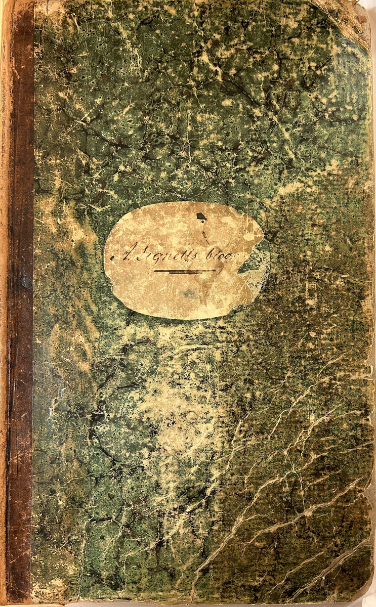 I kartongband med skinnrygg och grönsvart, marmorerat pärmpapper. I folioformat. Oval, liggande etikett på framsidan med handskriven titel.