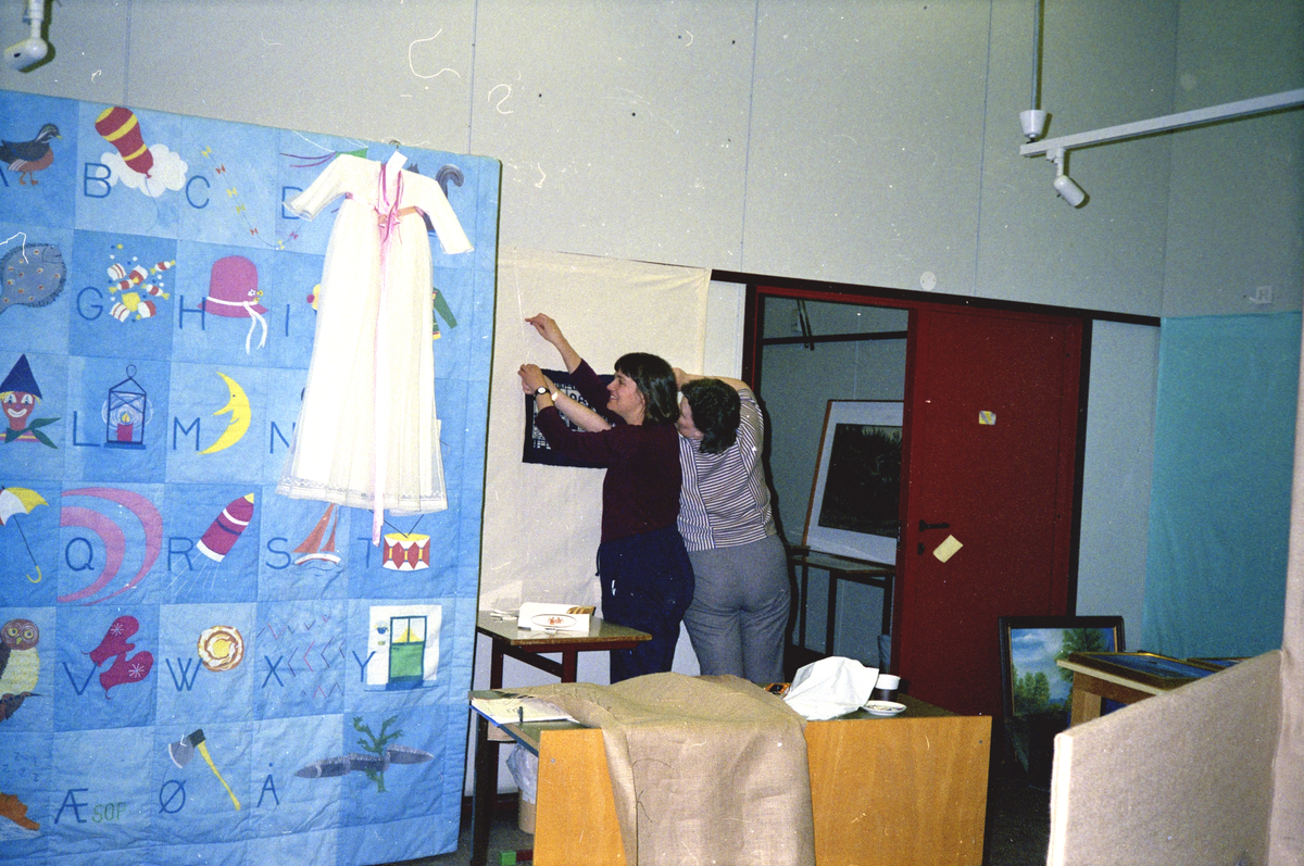 Kronprinsparet besøker Hitra 1989 : Forberedelser, Anne Britt Berg (høyre) og Amy Lightfoot henger på plass et broderi.