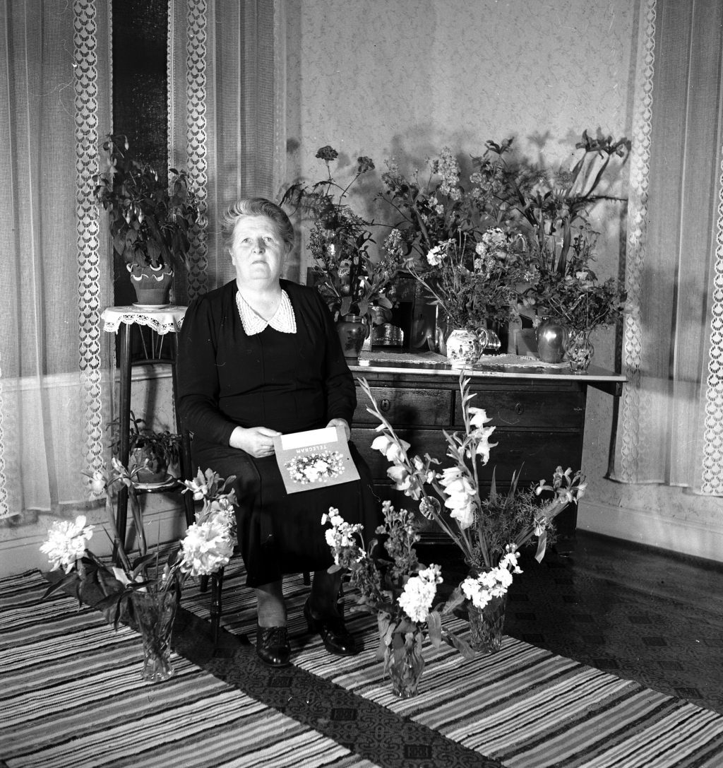 Kvinna sittandes vid blomsterbord.