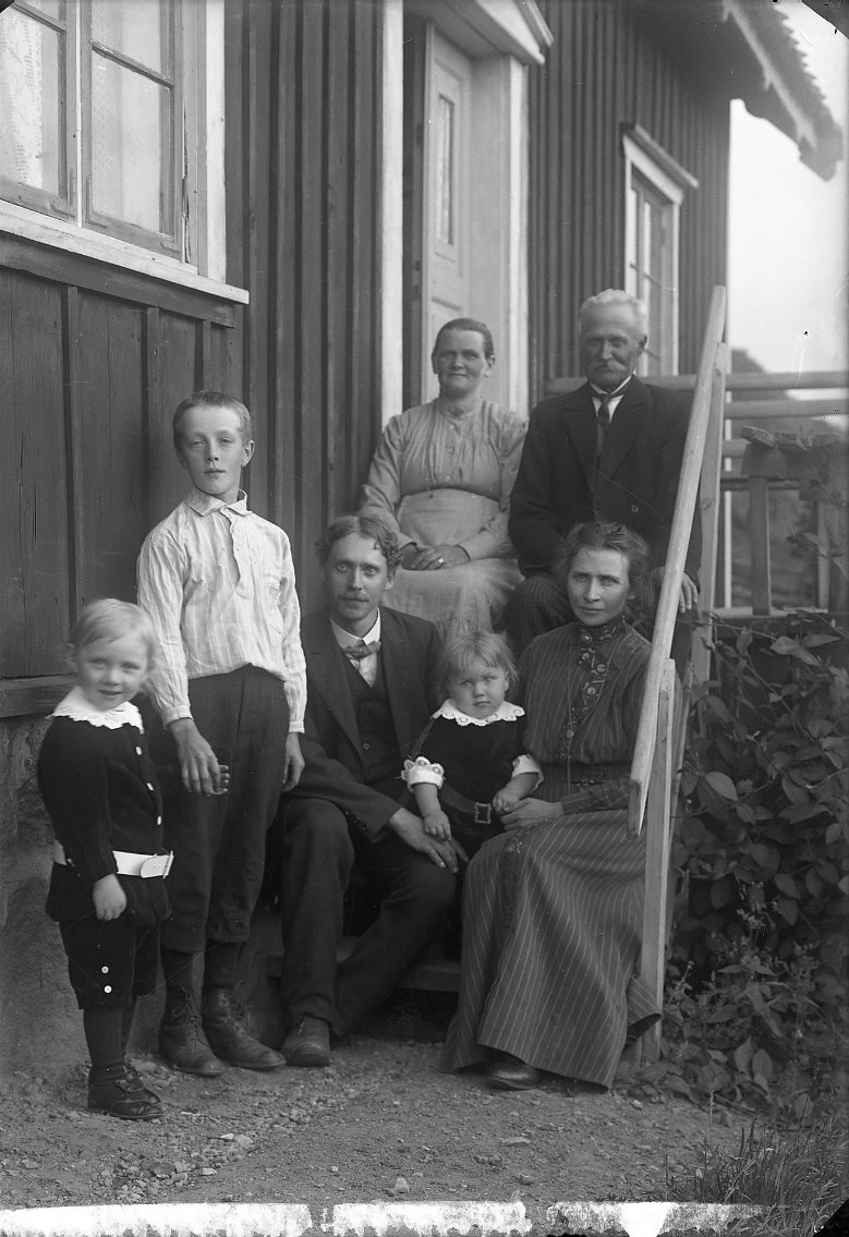 Sju personer, barn och vuxna, sitter på trappan till ett hus vid Grännabergets fot i Uppgränna.