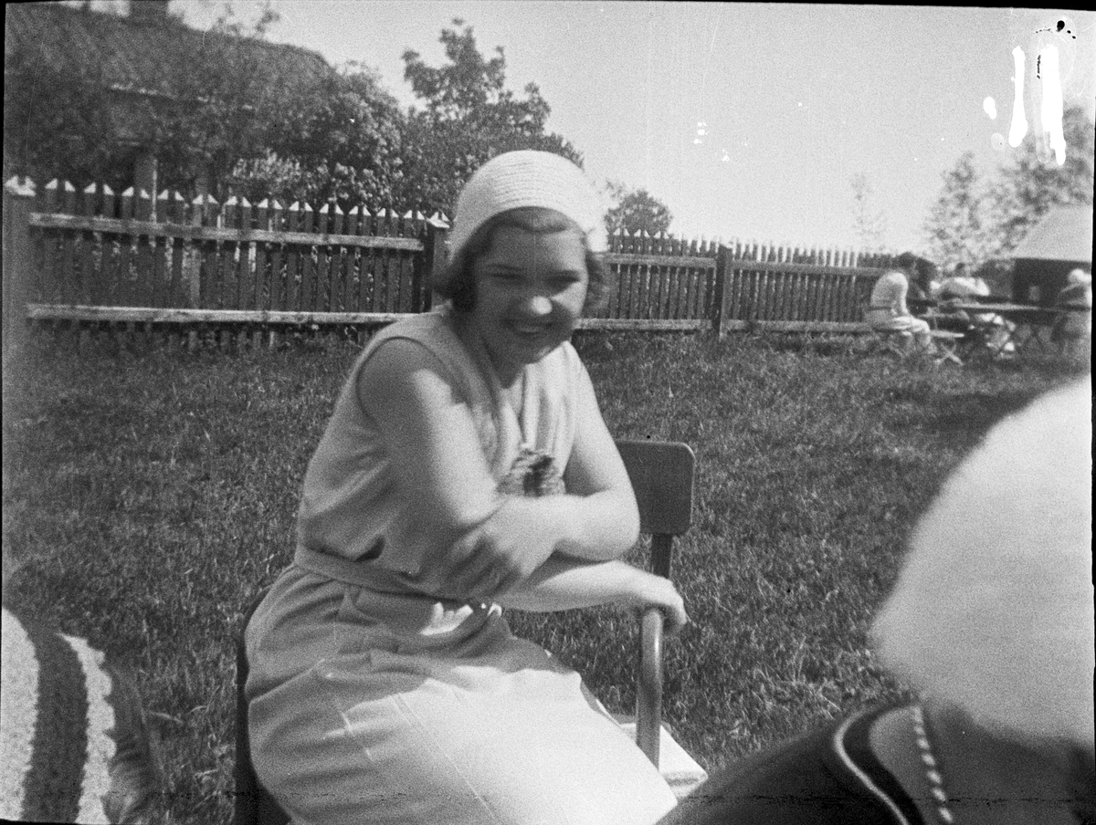 Kvinna sitter på stol i trädgård, Uppland