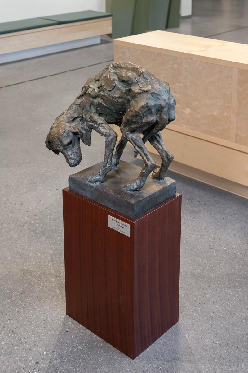 Skulpturen avbilder en hund stående med krummet rygg og halen mellom bena. 