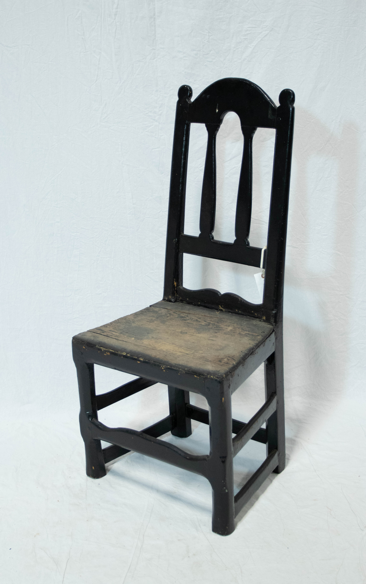 Trestol med høy rygg. Stolen er malt svart, med litt slitasje på setet. Stolen har en frontsprosse, to sidesprosser og en baksprosse.