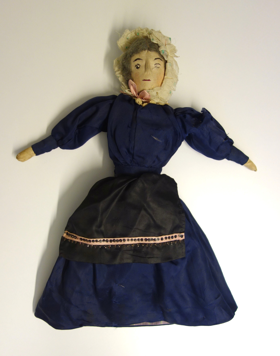 Dobbel dukke som kan "vrenges". Dukken på den ene siden har blå silkekjole. På den andre siden har dukken en enklere, rutete kjole.