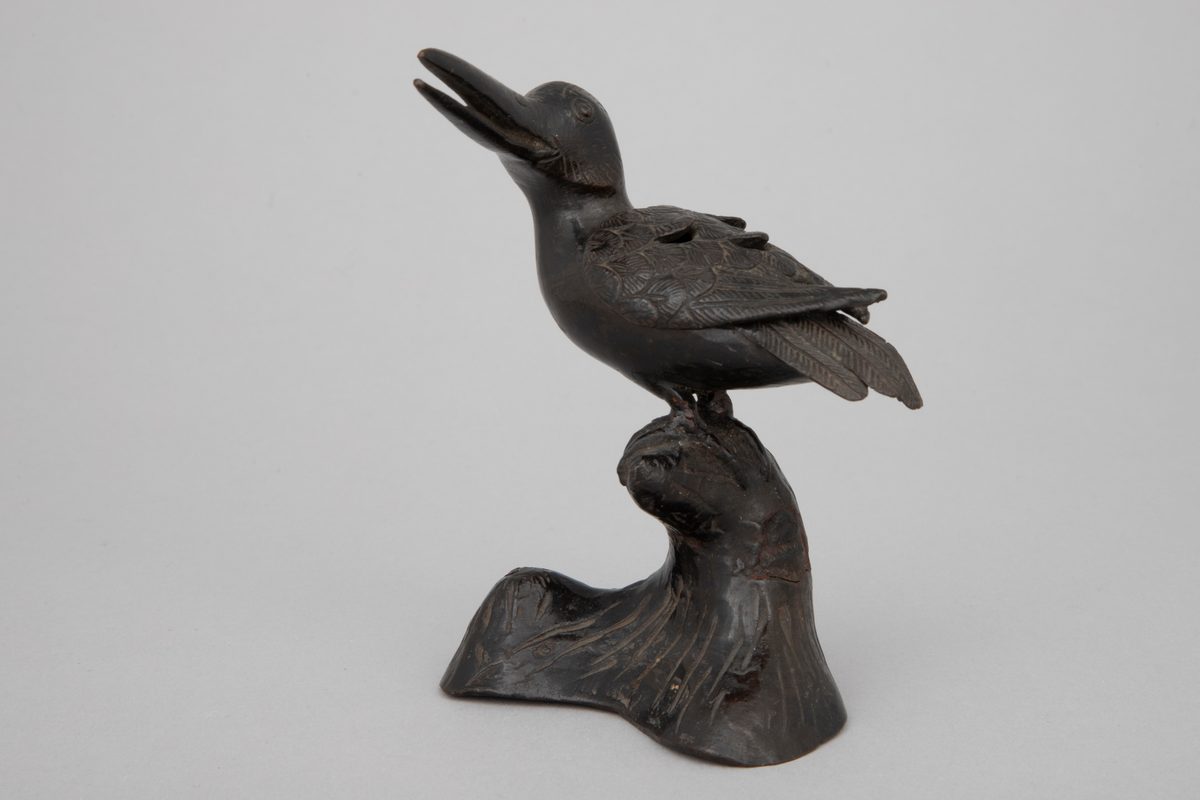 Røkelseskar utformet som fugl i støpt bronse. Løst vingeparti som kan løftes av som lokk. Fuglen sitter på hvelvet, svunget fotstykke. Patinert, mulig lakkert. Vinger, haleparti og deler av hode er siselert.