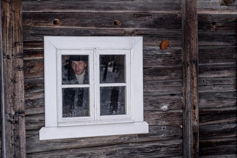 Bildet vier et vindu med en person i en eldre bygning.
