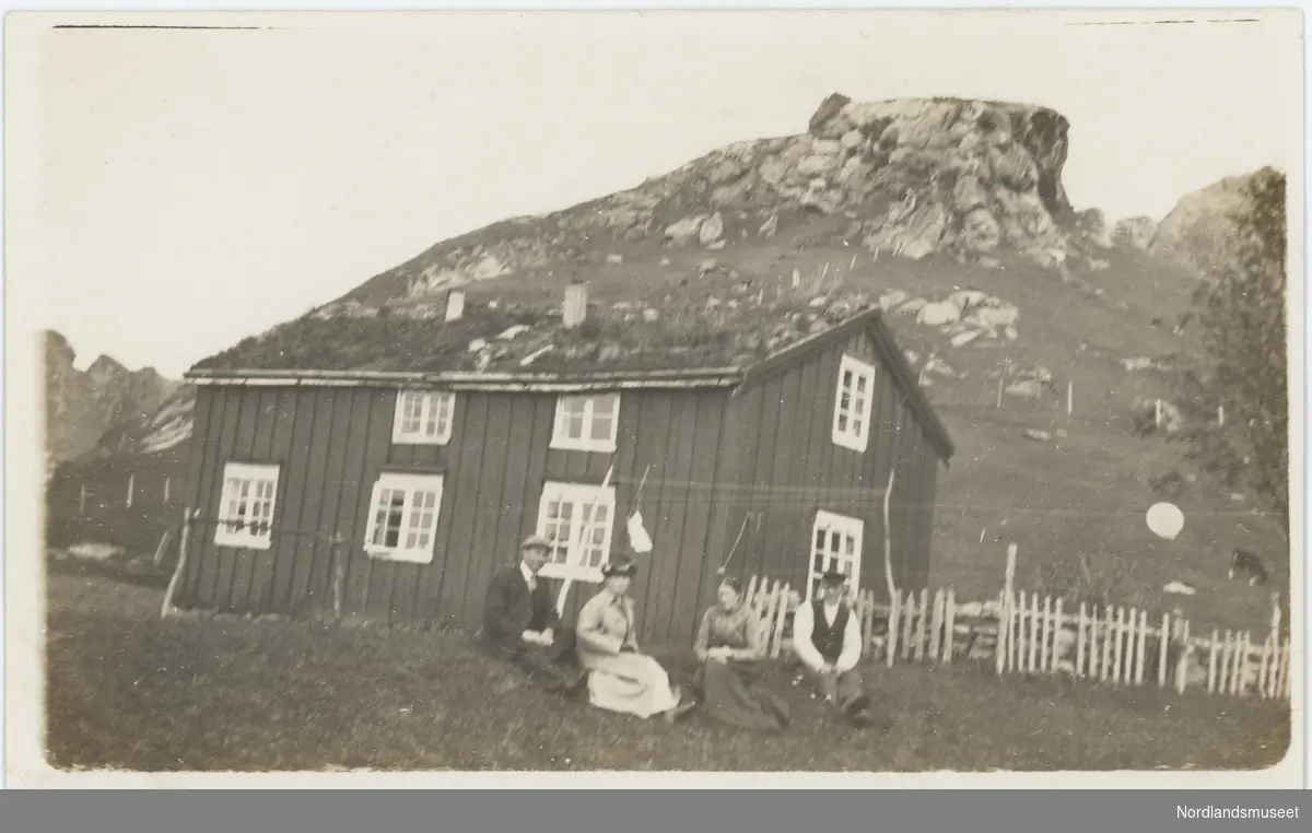 Fire mennesker (to menn, to kvinner) foran et Nordlandshus. Huset til Jentoft Johannesa under Dunberget.