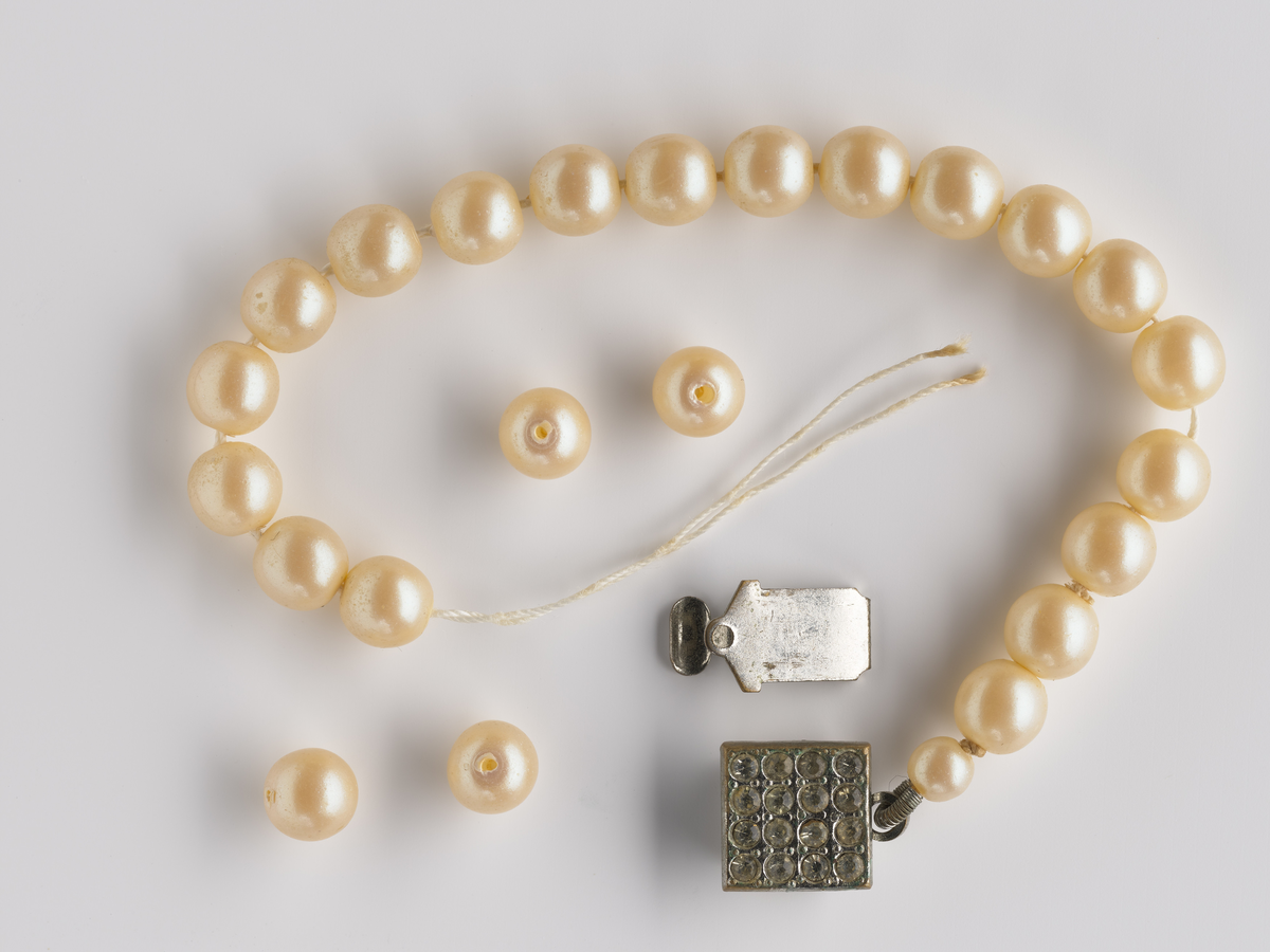 Perlearmbånd med en kvardatisk lås utsmykket med diamanter eller krystall. Armbåndet har 24 perler, og fire av dem ligger løst sammen med den andre låsen. 

Diverse cocktail-kjoler og smykker som har tilhørt Synnøve Brændshøi. De fleste er nok fra 40- og 50-tallet. Noen kjoler mangler merkelapp. De fleste er laget av naturfiber, bomull og silke. Noen i polyester/kunstfiber.