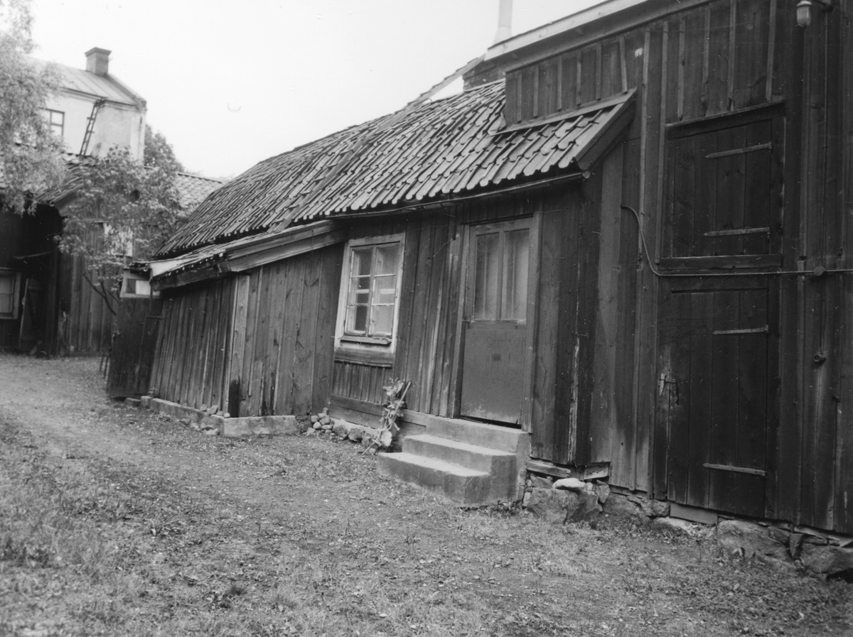 Gårdsinteriör från relativt centrala Linköping som minner om socioekonomiskt svagare tider. I kvarteren Arbetaren och Aspen trängdes äldre tiders träkåksbebyggelse in i modern tid. Under 1970-talet tillkom det storskaliga äldreboendet Aspen i området och för att ge plats revs åtskilliga hus. Även Biblioteksgatan lades igen och kvarteret Arbetaren gick upp i Aspen. Många historiska hus räddades dock. Några renoverades för att integreras med äldreboendet. Gårdslängan Hunnebergsgatan 5-9 restaurerades mer varsamt för ny funktion som hantverksgårdar. Bilden visar innergården till en av dem, Hunnebergsgatan 9. Längans borte del bestod av två sammanbyggda bostadshus. Mot dessa hade uthuset med möjlig höskulle byggts. Allt kvarstår om än i annan användning.