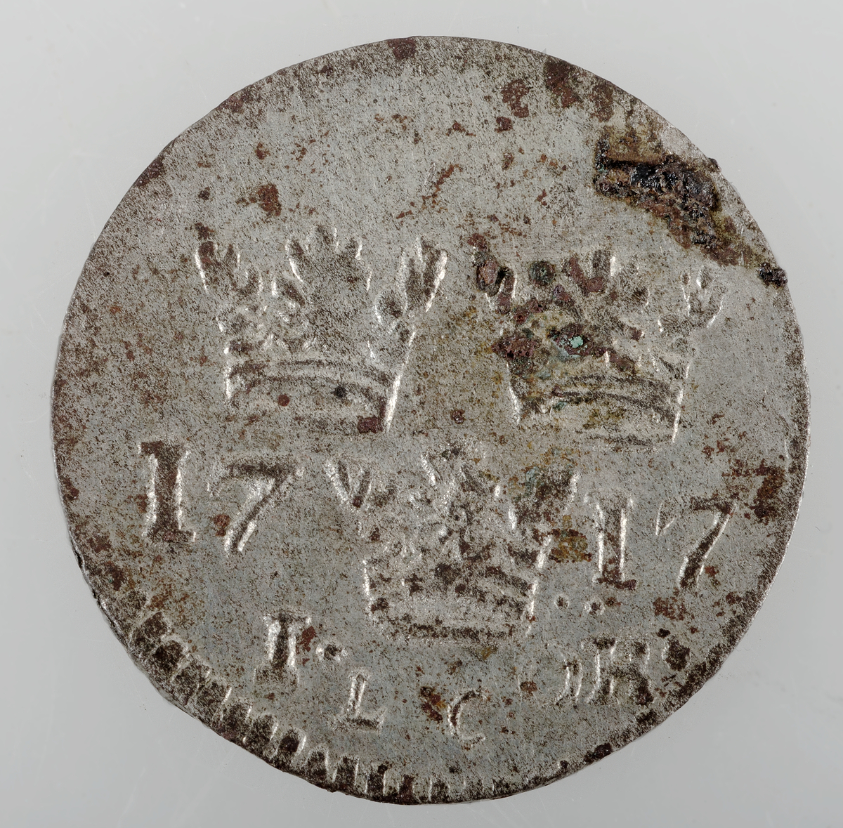 Mynt av silver. 1 öre 1717 (Karl XII), präglat i Stockholm.