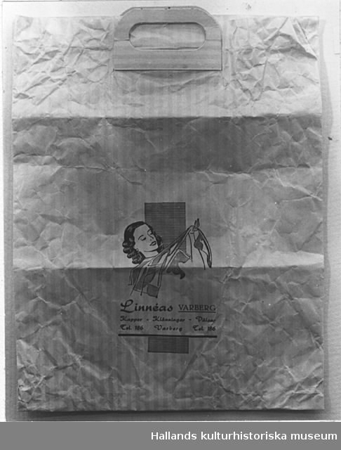 Påse av papper, handtag av papp. På ena sidan tryckt i svart:"Linnéas VARBERG kappor - klänningar - pälsar Tel. 186 Varberg Tel 186", samt bild av en kvinna, hållande i en silkesstrumpa.Höjd: 44 cm. Bredd: 33,5 cm.