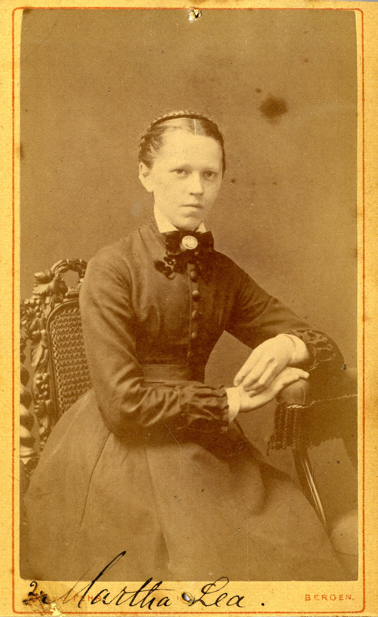 Portrett av ung kvinne sittende på stol.