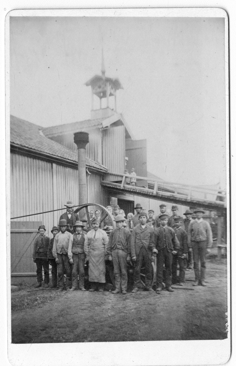 Foto av arbeidere foran lokomobil. Foto tatt i 1882