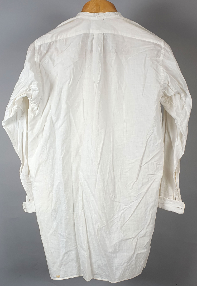 Hvit skjorte bryststykke med vertikale folder og knapper. Splitt i sidene. Til skjorten følger en løskrage.