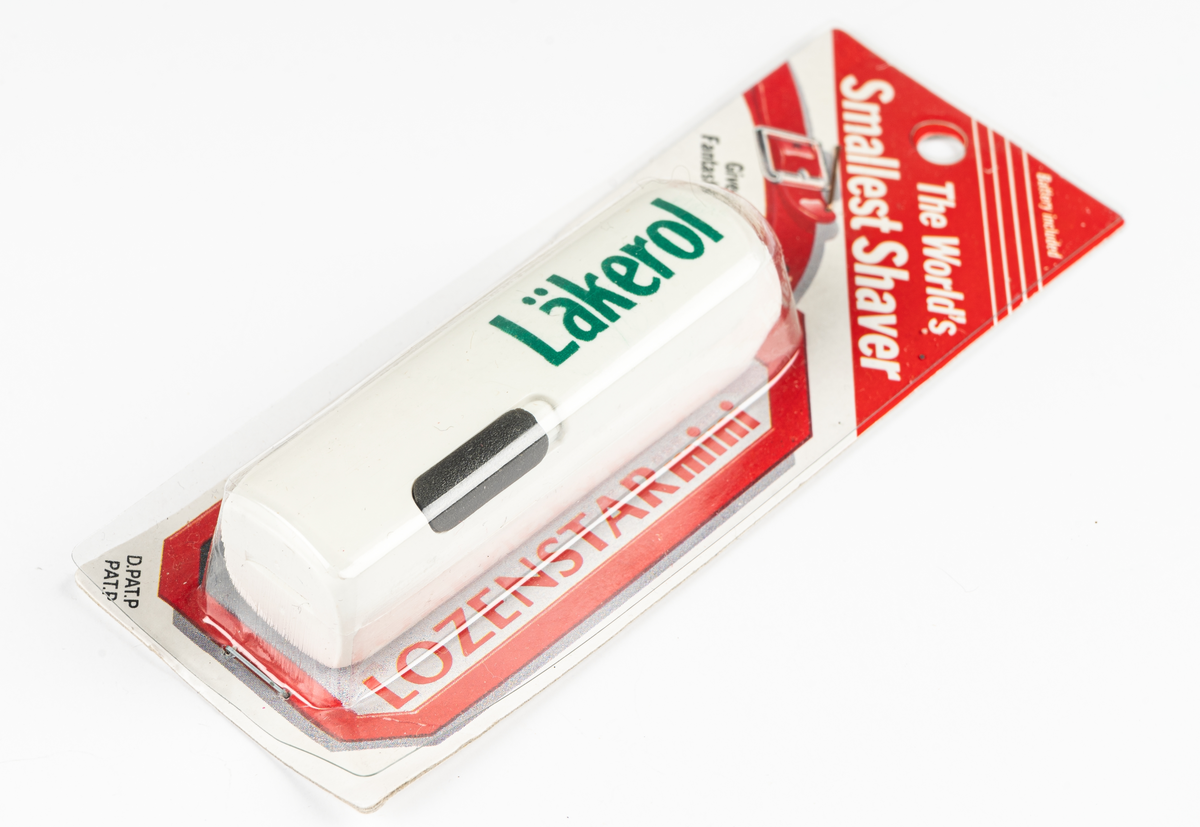Rakapparat, batteridriven, vit med grön text "Läkerol". I vit och röd plastförpackning.