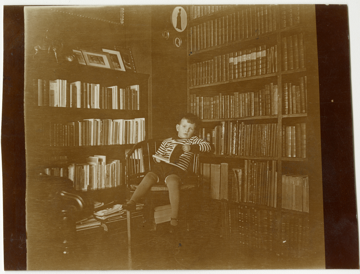 Foto av gutt i privat bibliotek, ca. 1915. Trolig Niels Frederik Aall