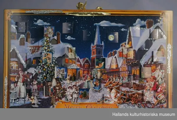 Adventskalender av papper med glitter. Motiv: tomtar och barn, en julgran samt hus i bakgrunden. Märkt på framsidan: "Merry Christmas". Guldfärgad tygrosett upptill.