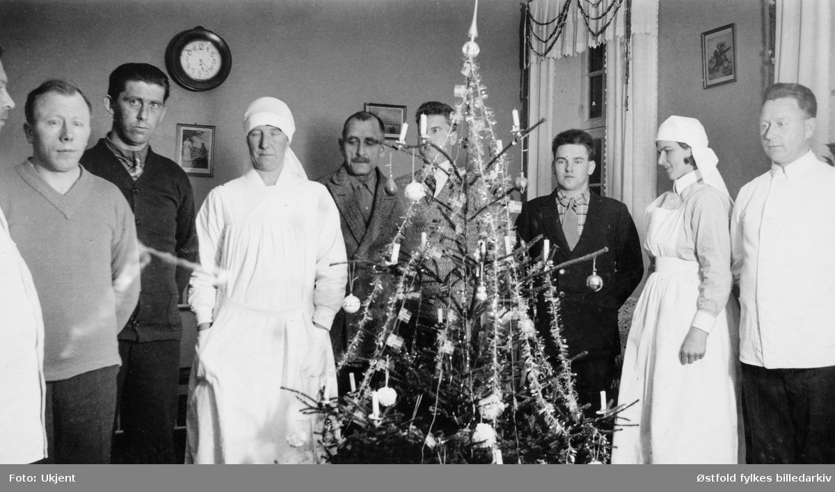 Julefeiring på Veum asyl/ psykeatriske sykehus, ansatte og pasienter står rundt juletre. Aagot Koren, ansatt ved sykehuset, nr 4 fra venstre.