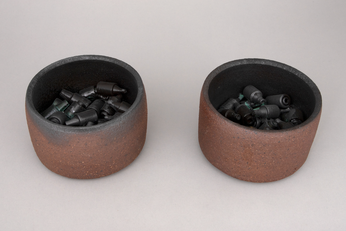 To sylindriske skåler i kobberoksidert steingods med funnene sikringer.