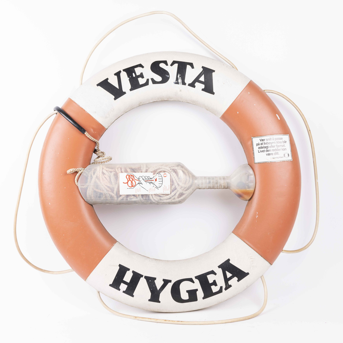 Rund livbøye med påskrift VESTA HYGEA i plast med redningsssnor i plastbeholder montert i midten av bøyen.