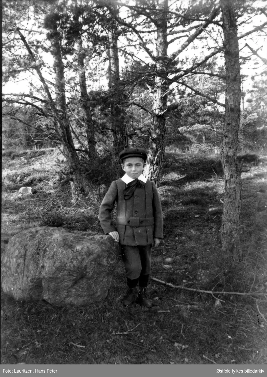 Ukjent gutt ved sten i skogen.