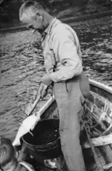 Mann fisker i en robåt.